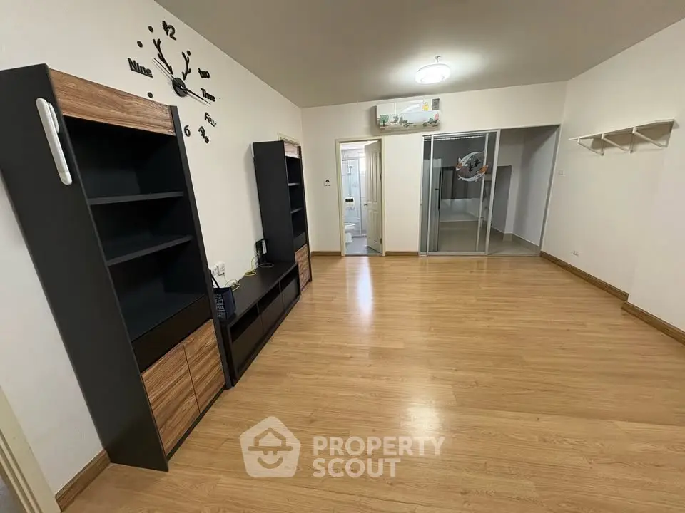 Spacious living room with modern wooden flooring and stylish shelving units.