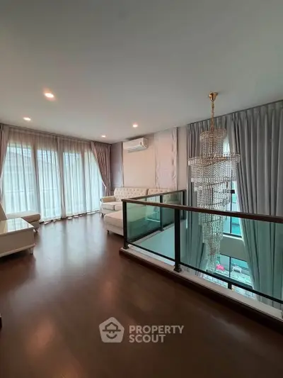 Luxurious living room with elegant chandelier and floor-to-ceiling windows in modern apartment.