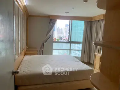 Cozy bedroom with city view and natural light, featuring a comfortable bed and wooden furnishings.