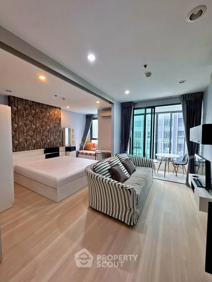 Spacious modern studio apartment with stylish decor and balcony view.