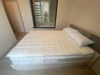 Spacious bedroom with modern decor and large window offering natural light.
