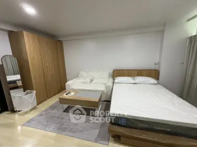 Modern studio apartment with cozy bed, stylish sofa, and sleek wardrobe in a well-lit space.