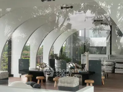 Stunning modern living room with arched windows and lush greenery views, featuring stylish furniture and decor.
