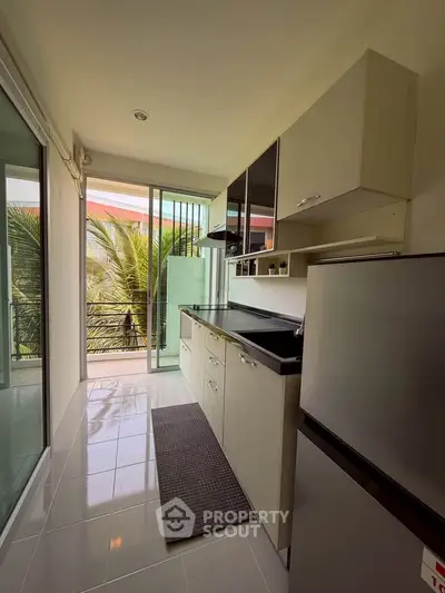Modern kitchen with sleek cabinetry and balcony view, perfect for culinary enthusiasts.