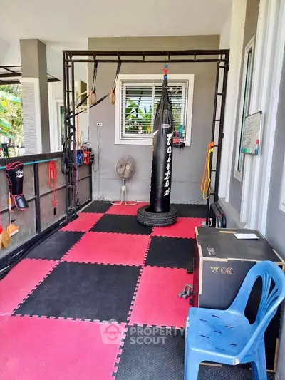 Home gym with punching bag and exercise equipment on red and black mats