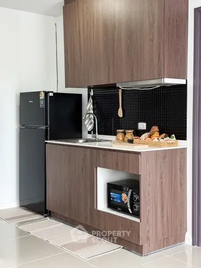 Modern kitchen with sleek cabinets, black fridge, and stylish backsplash
