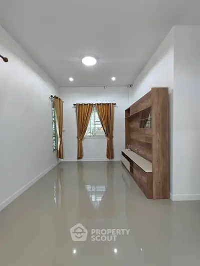 Spacious living room with elegant wooden TV unit and glossy tiled floor, featuring large windows with golden curtains.