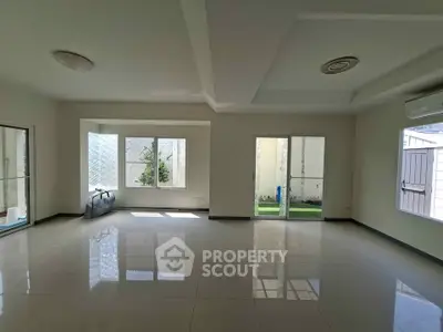Spacious modern living room with large windows and glossy tiled floors