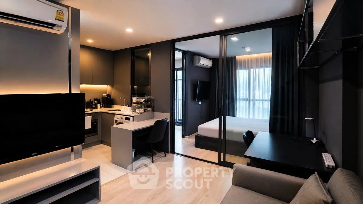 Modern open-plan living room with sleek kitchen and cozy bedroom in stylish apartment.