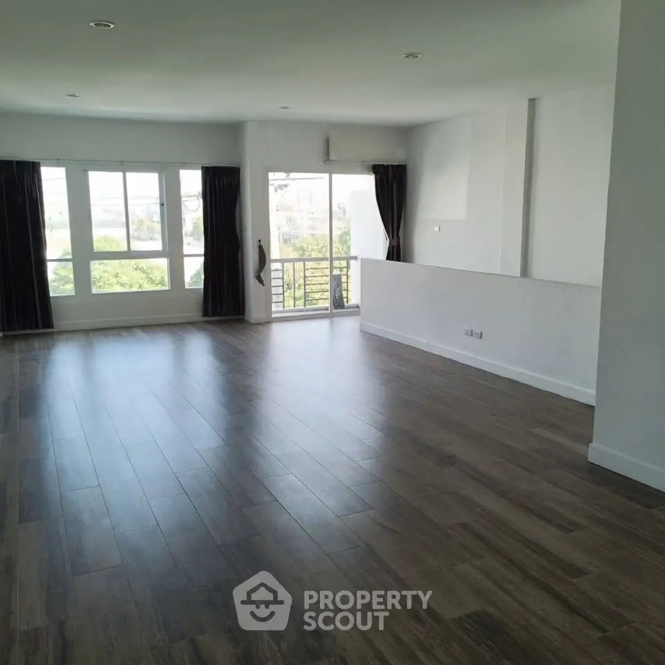 Spacious empty living room with large windows and wooden flooring