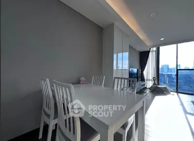 Modern living room with dining area and city view, featuring sleek furniture and large windows.
