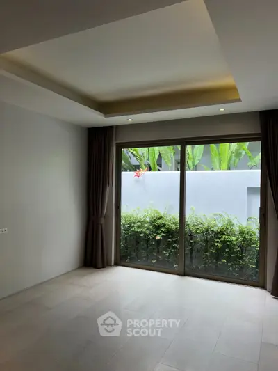 Spacious room with large window and garden view, perfect for modern living.