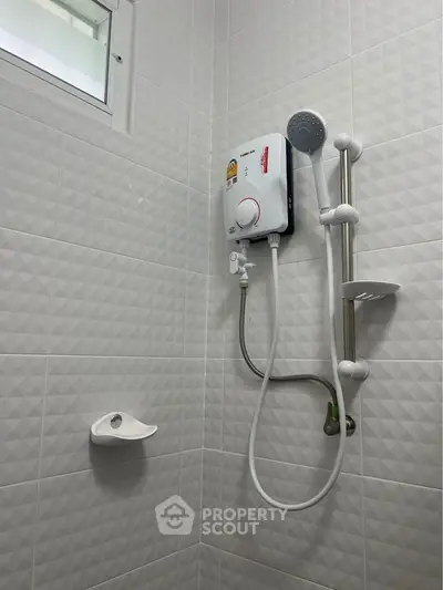 Modern bathroom with electric shower and textured white tiles.