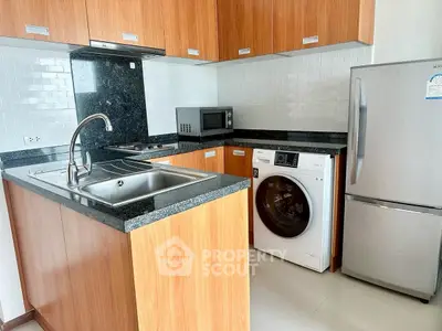 Modern kitchen with wooden cabinets, washing machine, and stainless steel appliances.