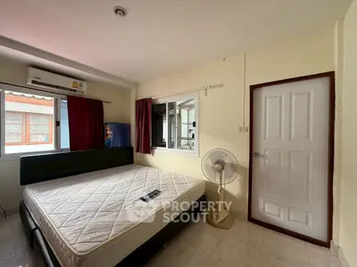 Cozy bedroom with large window and air conditioning, featuring a comfortable bed and fan for a relaxing atmosphere.