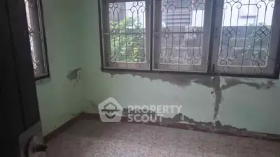 Room with peeling paint and barred windows, potential for renovation.