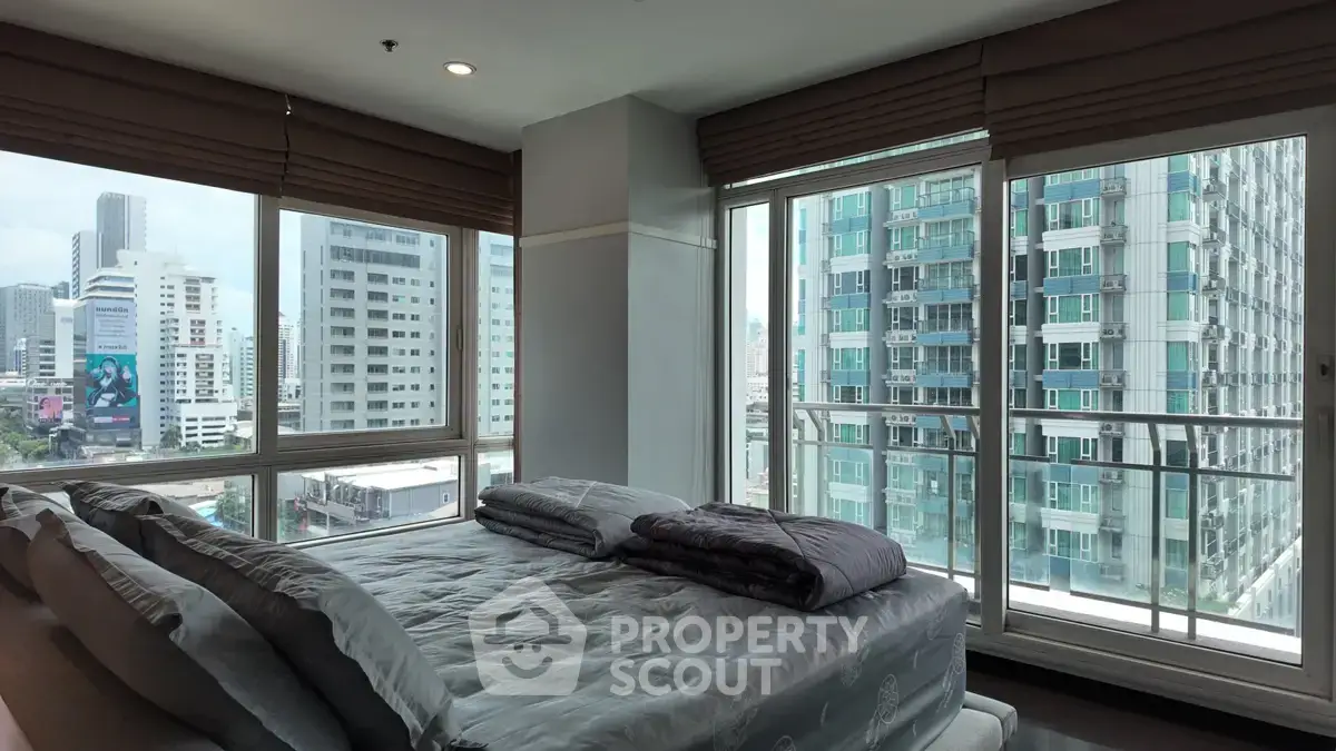 Spacious bedroom with panoramic city views in a modern high-rise apartment.