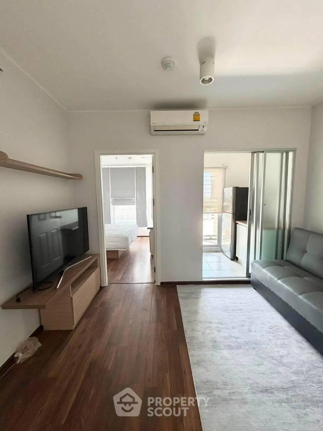 Modern living room with sleek furniture and air conditioning, leading to a bright bedroom.
