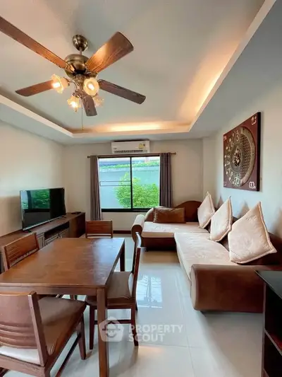 Charming living room with modern decor, ceiling fan, and natural light from large window.