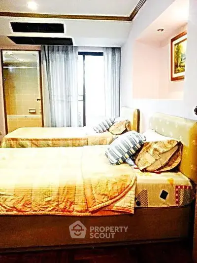 Cozy bedroom with twin beds and large window offering natural light.