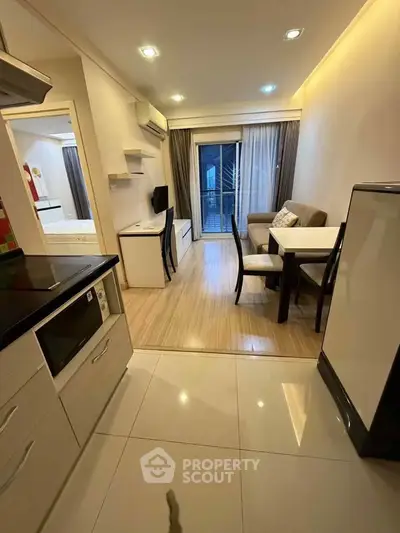 Modern apartment with open layout kitchen and cozy living area, featuring sleek furniture and balcony access.