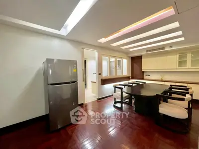 Spacious dining area with modern lighting and sleek refrigerator