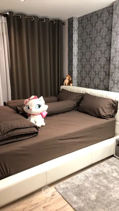 Cozy bedroom with elegant wallpaper and plush toys on a stylish bed, perfect for relaxation.