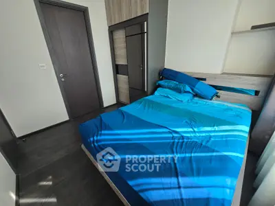 Modern bedroom with sleek design and blue bedding, featuring a built-in wardrobe and wooden flooring.