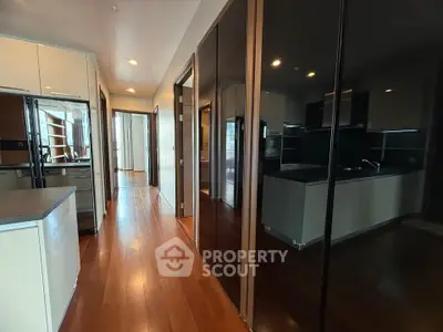 Spacious modern kitchen with sleek appliances and wooden flooring in a luxury apartment.