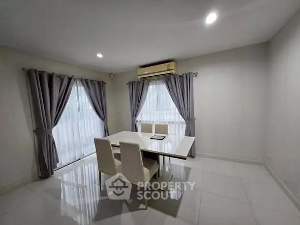 Spacious dining area with elegant table and chairs, featuring large windows and modern lighting.