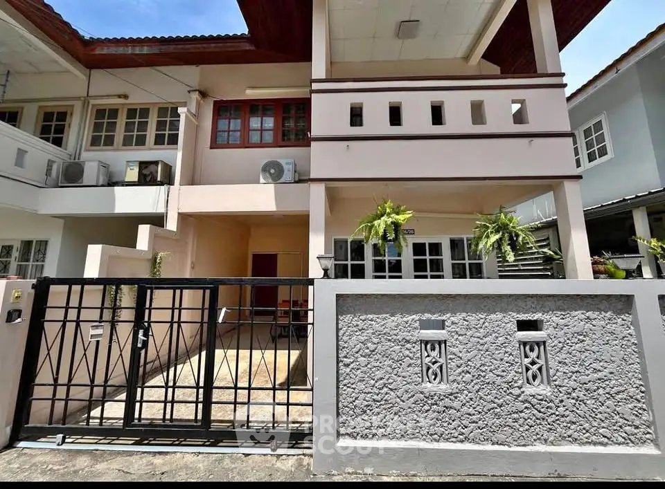 Charming two-story townhouse with gated entrance and modern exterior design.