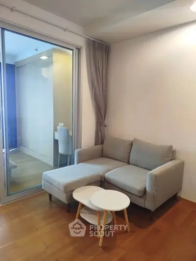Modern living room with cozy gray sofa and stylish nested coffee tables, featuring a wooden floor and sliding glass door.