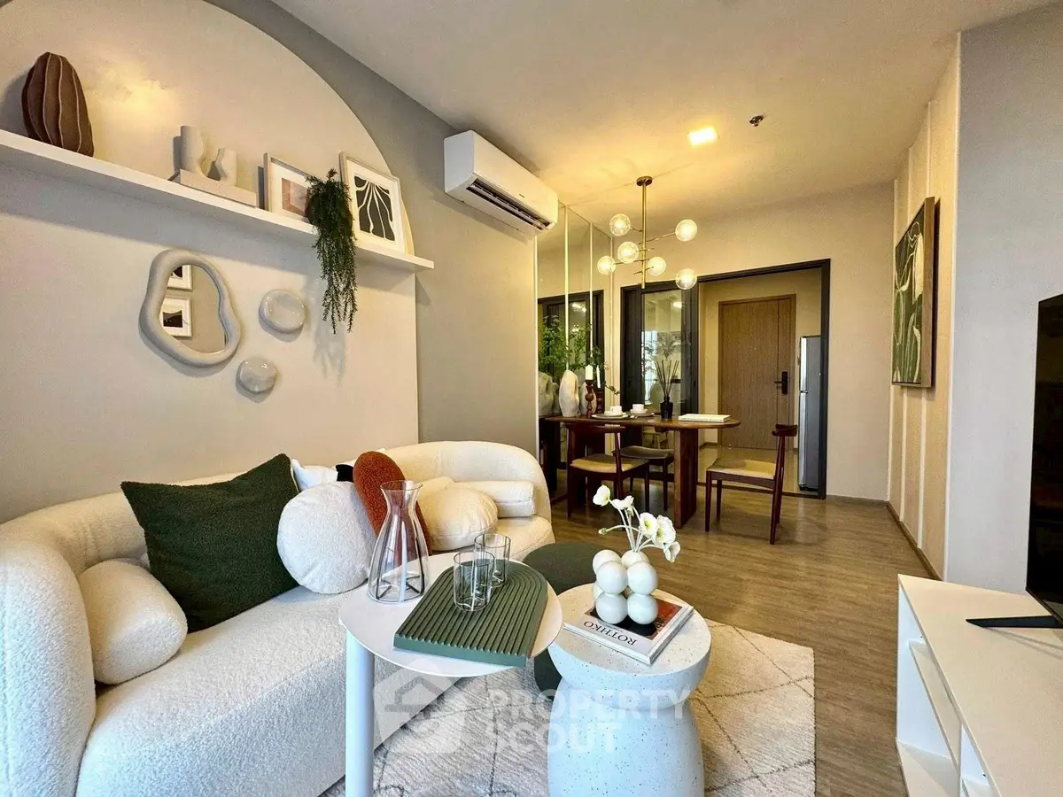 Modern living room with stylish decor and open dining area, featuring elegant lighting and cozy seating.