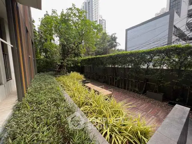 Modern urban garden with lush greenery and wooden deck in a high-rise building setting.