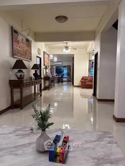 Spacious living room with elegant decor and polished floors, featuring a cozy seating area and stylish artwork.