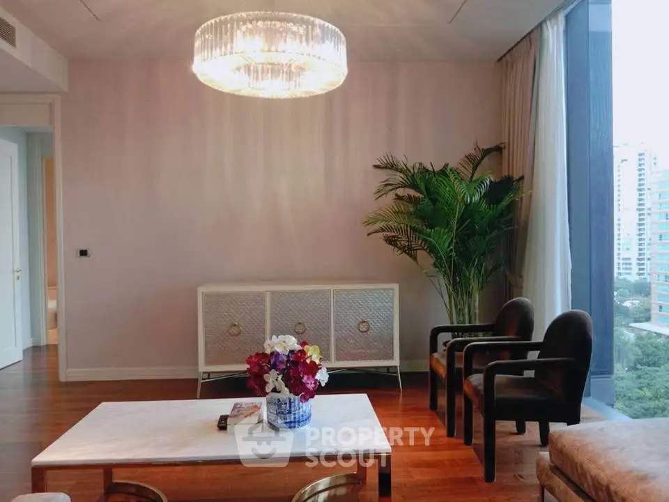 Elegant living room with modern chandelier, large window view, and stylish furniture in a high-rise apartment.
