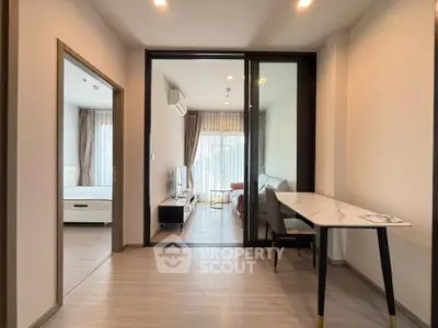 Modern apartment interior with open living room and bedroom, featuring sleek furniture and natural light.