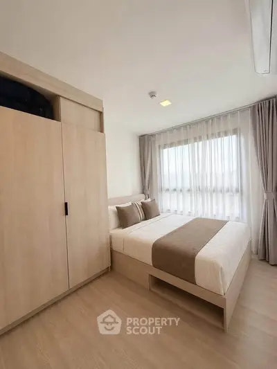 Modern bedroom with natural light, featuring a cozy bed and stylish wooden wardrobe.