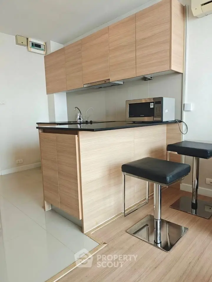Modern kitchen with sleek wooden cabinets and breakfast bar in a stylish apartment.