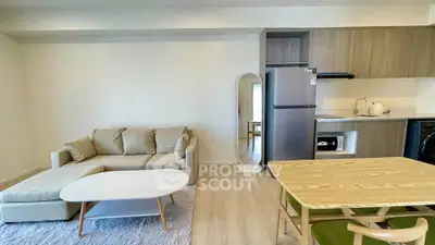 Modern living room with cozy sofa, dining table, and sleek kitchen appliances in open layout.