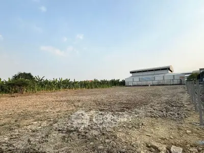 Expansive vacant land with potential for development, surrounded by lush greenery and clear skies.