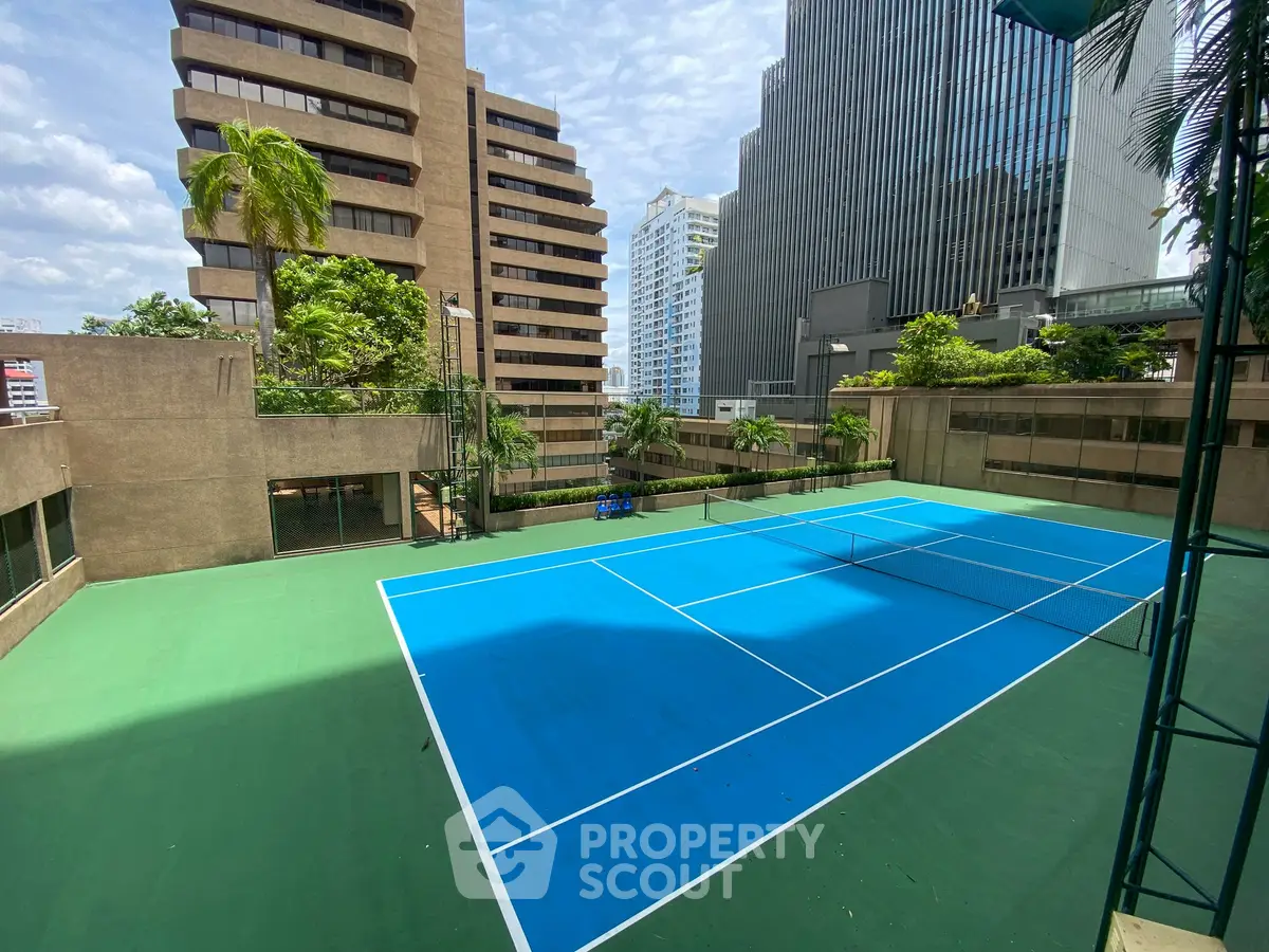Urban tennis court surrounded by modern high-rise buildings, offering a vibrant city lifestyle.