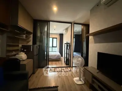 Modern apartment interior with open layout, featuring a cozy living area and bedroom separated by glass doors.