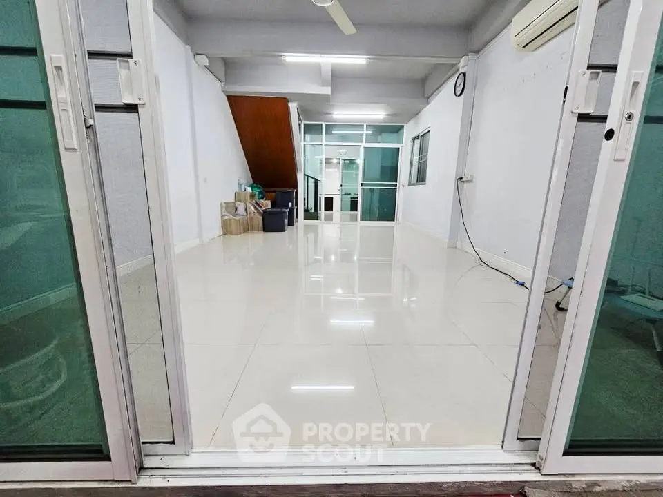 Spacious open-plan living area with sleek tile flooring and modern sliding glass doors.