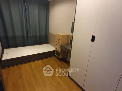 Cozy minimalist bedroom with wooden flooring and ample storage space.