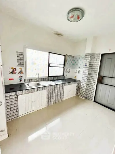 Spacious kitchen with modern design and ample natural light, featuring sleek countertops and stylish cabinetry.