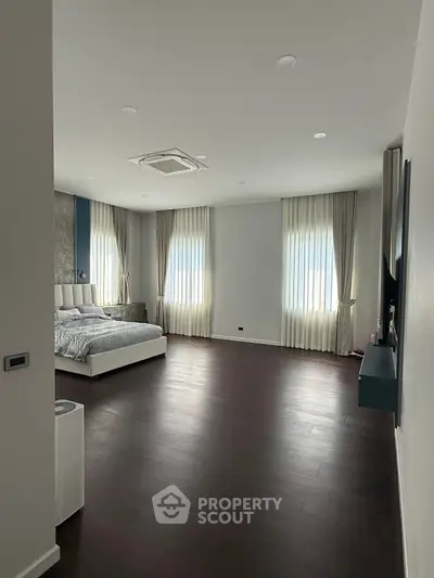 Spacious modern bedroom with elegant curtains and hardwood flooring