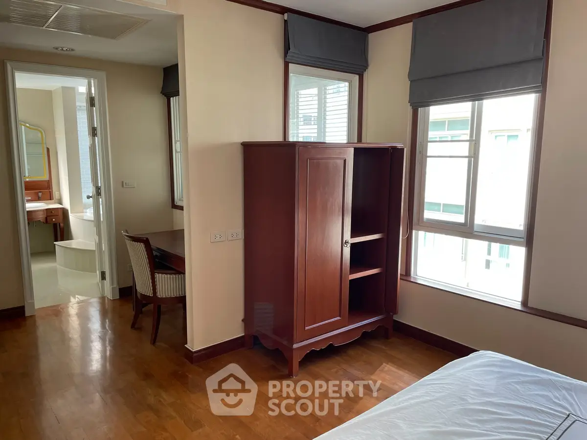 Spacious bedroom with wooden furniture and natural light in modern apartment