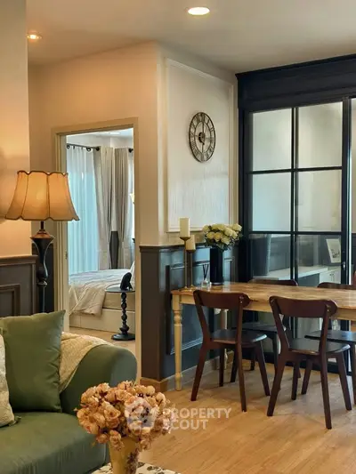 Charming living room with elegant decor and cozy dining area, featuring a glimpse into a stylish bedroom.