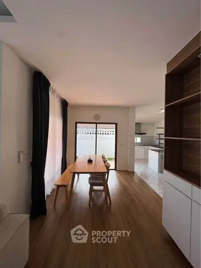 Spacious dining area with wooden flooring and modern open kitchen design